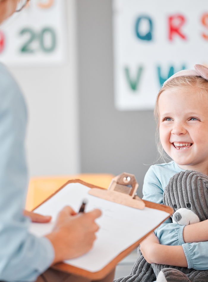 Young girl smiling and laughing looking at doctor with clipboard Young girl smiling and laughing looking at doctor with clipboard